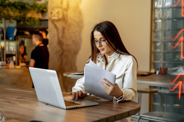 Attractive woman in casual clothing sitting at table with delicious meal while working on laptop. Happy girl with brown hair spending time at modern restaurant. - 写真・画像