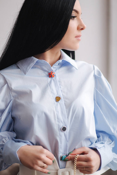 Atrakcyjna młoda modelka demonstrująca ubrania. Wiosenne kolekcje eleganckiej brunetki. Niebieska koszula - Zdjęcie, obraz