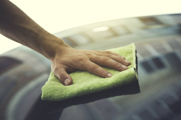 молодой человек чистит синий капот автомобиля
 - Фото, изображение