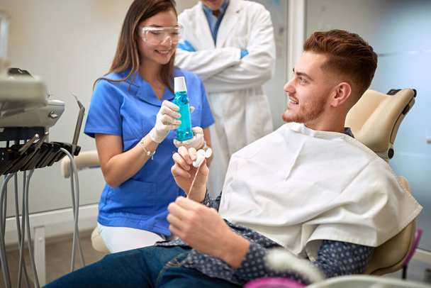 Man at dentist looking at dental floss for cleaning teeth - Fotoğraf, Görsel