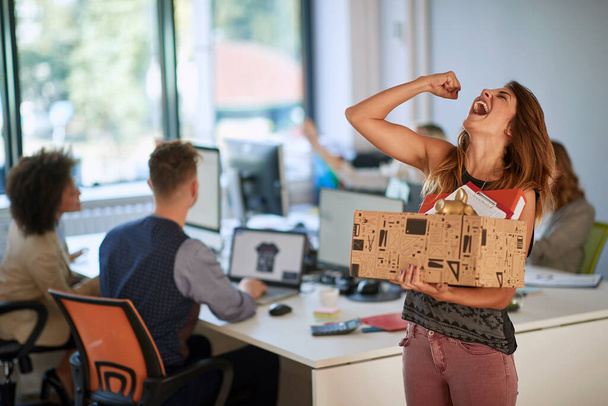 Happy successful modern  woman moving box with stuff at new modern business company. - Фото, изображение