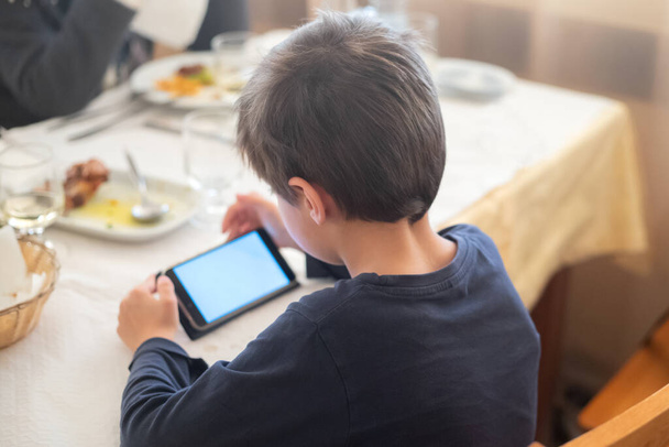 boy playing with smartphone in restaurant - Foto, Imagem