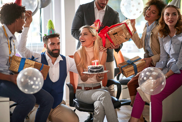 Zespół biznesowy świętuje urodziny szczęśliwego kolegi w nowoczesnym biurze - Zdjęcie, obraz
