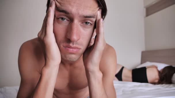 Pariskunnalla on ongelmia sängyssä. Huolestunut mies istuu sängyllä tuntuu surulliselta ja levottomalta, seksuaalisista ongelmista, suhteiden vaikeuksista
 - Materiaali, video