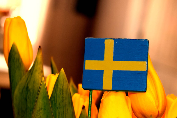 Švédská vlajka uprostřed žluté kytice tulipánů - Fotografie, Obrázek
