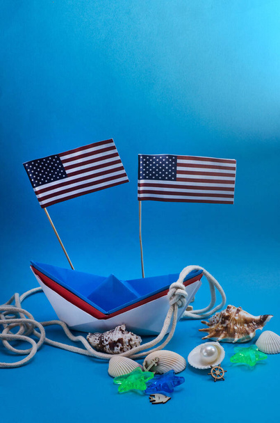 Szczęśliwego Dnia Kolumba. Papierowa łódka na niebieskim tle z przestrzenią do kopiowania z amerykańskimi flagami. Koncepcja wakacji USA. - Zdjęcie, obraz