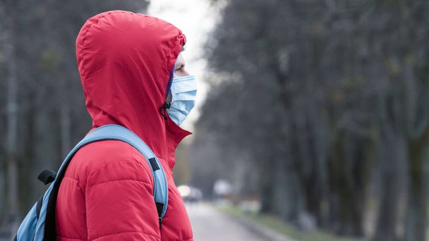 Lähikuva muotokuva nuorten eurooppalaisten mies suojaava kertakäyttöinen lääketieteellinen kasvonaamio kävely ulkona. Uusi koronavirus (COVID-19). Terveydenhuollon käsite epidemian tai pandemian aikana
 - Valokuva, kuva