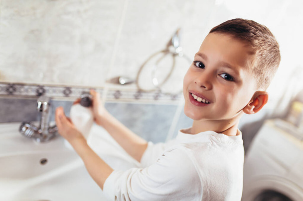 Netter Junge wäscht sich im Badezimmer die Hände. Schutz vor Viren und Bakterien. - Foto, Bild