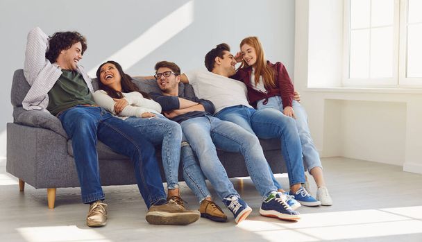 A group of friends is sitting on couch in a room on a gray background. - Foto, Imagem