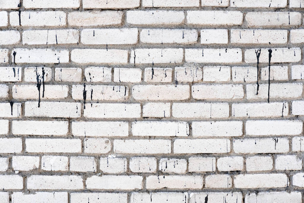 Blanc mur de brique sale texture arrière-plan. Mur avec peinture noire coulée. Vieilles briques altérées et fissurées se rapprochent. Espace de copie
 - Photo, image