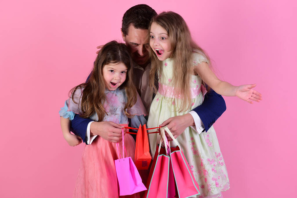 Shopping and surprise concept. Schoolgirls and father hold pink packets - Foto, afbeelding