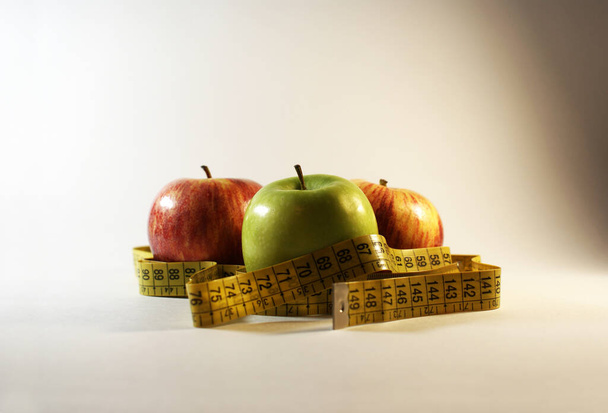 Apples and tape for measuring body volume, diet. - Φωτογραφία, εικόνα