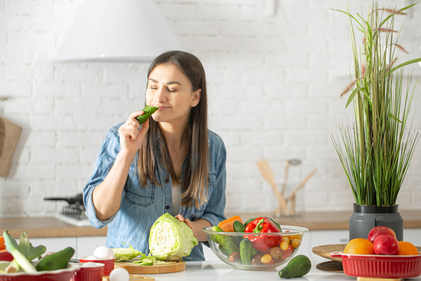 Eine junge schöne Frau bereitet in der Küche einen Salat mit verschiedenen Gemüsesorten zu. Das Konzept einer gesunden Ernährung und Lebensweise. - Foto, Bild