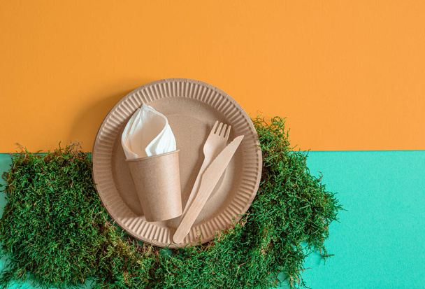 ECO Bastelpapiergeschirr. Pappbecher, Teller, Tüten, Fast-Food-Behälter und Holzbesteck mit Maisstärke auf orange-blauem Hintergrund. Recycling oder das Konzept der Abfallfreiheit. - Foto, Bild