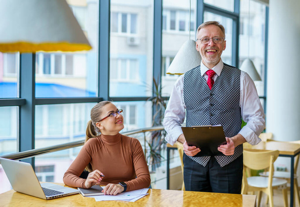 Senior businessman discussing business ideas with the assistance. Mature man and businesswoman in an office. Photo from the business lunch - Фото, зображення