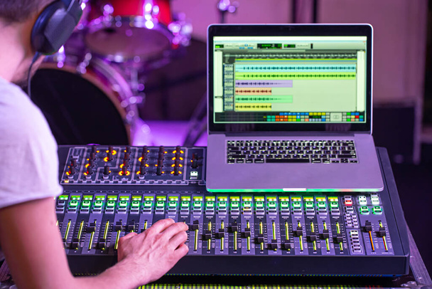 Digitale mixer in een opnamestudio, met een computer voor het opnemen van muziek. Op de achtergrond van de geluidstechnicus aan het werk. Het concept van creativiteit en showbusiness. - Foto, afbeelding