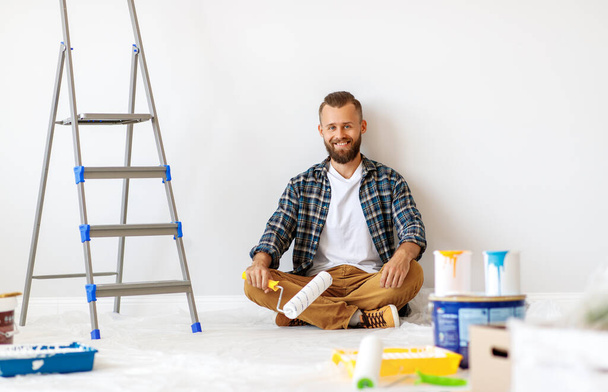Renovierung in der Wohnung. Glücklicher Mann bemalt die Wand mit Schmerz - Foto, Bild