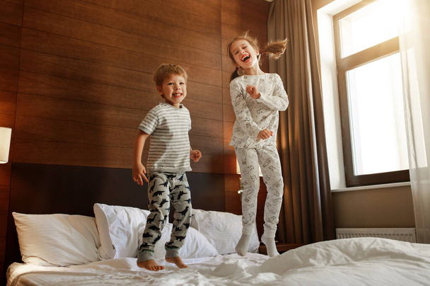 crianças felizes irmão e irmã saltar na cama no leito
 - Foto, Imagem