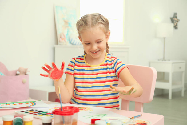 Cute little child painting with palms at table - Foto, afbeelding