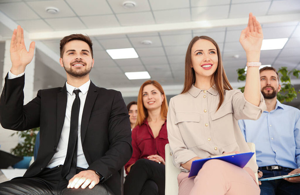 Personas levantando las manos para hacer preguntas en la formación empresarial en interiores
 - Foto, Imagen