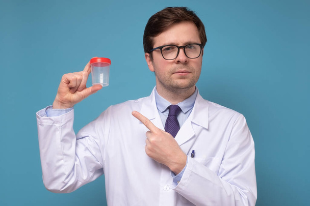 Médico caucaisano maduro ou cientista de laboratório segurando copo de amostra de urina
. - Foto, Imagem