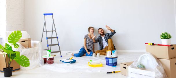 Young couple woman and boyfriend pointing away  while sitting near white wall and planning room interior during renovation in new apartmen - Fotografie, Obrázek