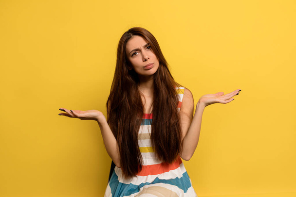 Front view of pensive adorable european woman. Stylish girl thinking and shruging over yellow background. - Photo, Image