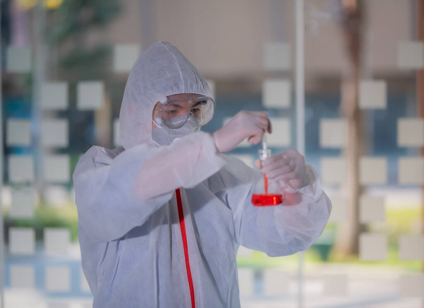 Mužský vědec testuje experiment ve vědecké laboratoři, kde drží zkumavku plnou chemické látky. Výzkumný pracovník analyzuje inovace související s medicínou. Mikrobiologický koncept. - Fotografie, Obrázek