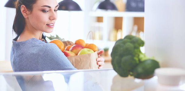 Smiling woman taking a fresh fruit out of the fridge, healthy food concept - Foto, Imagem