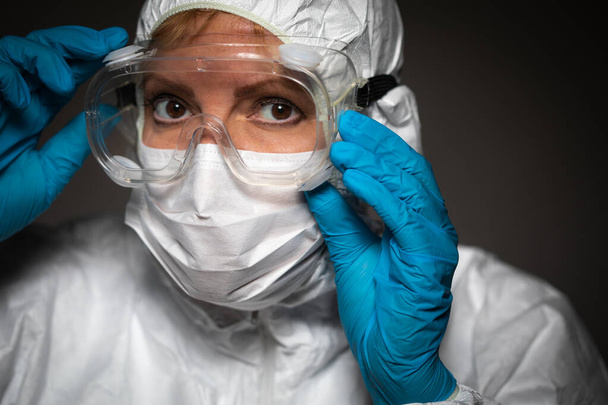 Trabajadora médica que usa mascarilla protectora y equipo contra el fondo oscuro. - Foto, Imagen