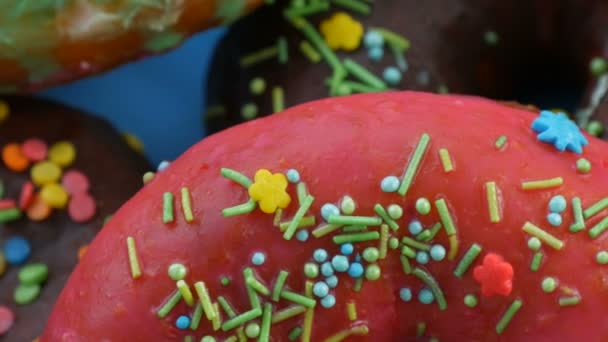 Amerikkalaisia donitseja värikkäillä lasitteilla ja jauheella. Kierrä sinisellä pohjalla lähikuva näkymä
 - Materiaali, video