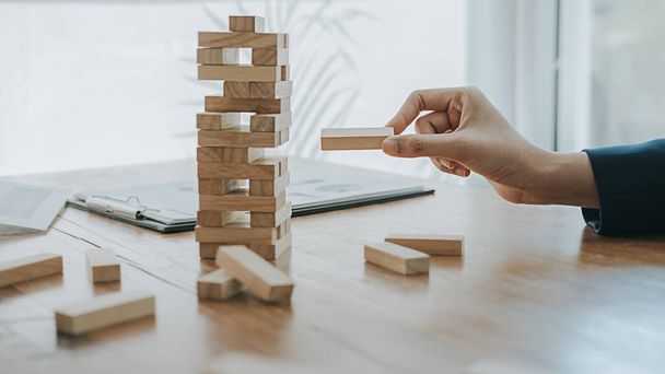 Hand of business people planning, risk and strategy in business.Businessman gambling placing wooden block on a tower. - Photo, Image