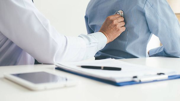 ασθενής, ακούγοντας με προσήλωση σε ένα αρσενικό ο γιατρός εξηγεί τα συμπτώματα των ασθενών ή μια ερώτηση, όπως συζητούν μαζί χαρτιά σε διαβούλευση - Φωτογραφία, εικόνα