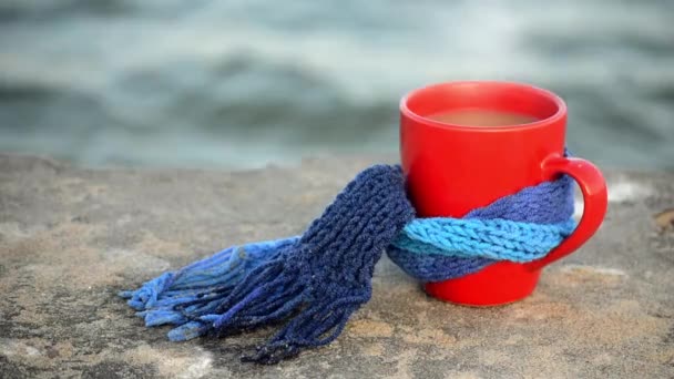 Red cup with hot coffee and steam tea, tied with blue knitted scarf - Footage, Video