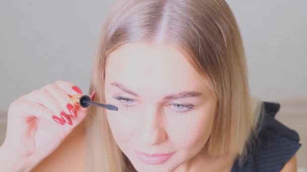 Confident happy young woman holding mascara apply on eyeleashes prepare getting ready in the morning, smiling beautiful girl doing make up put cosmetics on face looking in mirror in bathroom at home. - Footage, Video