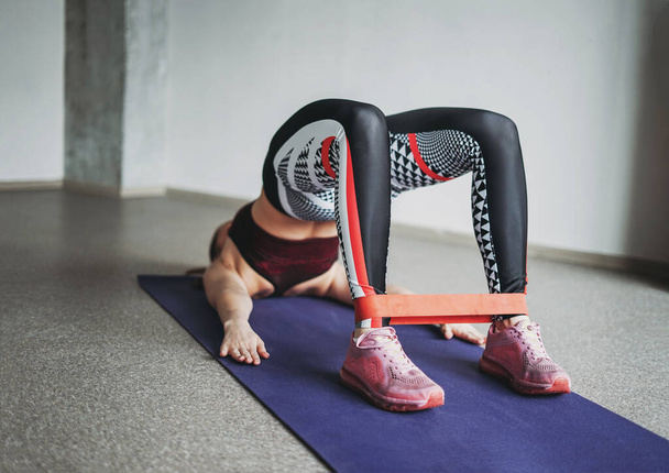 Attraktive Passform junge Frau Sport tragen Fitness-Mädchen Modell tun Stretching mit Gummiband machen Planke im Loft Studio Workout-Klasse - Foto, Bild