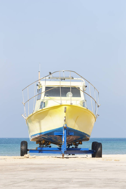 un bateau jaune se tient sur une remorque sur une plage de sable
 - Photo, image