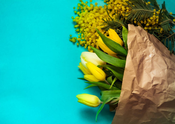A bouquet of yellow flowers on a craft background; spring flowers on a blurred blue  background - Foto, Imagen