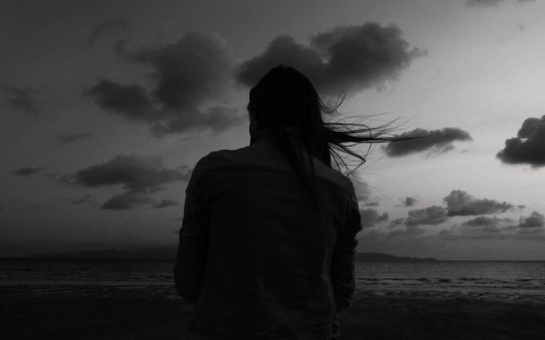 Samotna kobieta na plaży o zmierzchu wypatrująca morza - Zdjęcie, obraz
