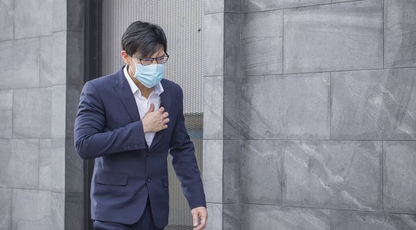 Empresário asiático veste um terno com tosse, espirros e usando uma máscara para evitar o surto do vírus covid19.. Concebe saúde e prevenção de doenças laxantes graves
. - Foto, Imagem