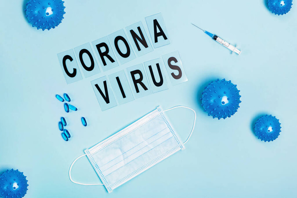 Abstract virus strain model of Coronavirus disease COVID-19, pills, syringe and mask on blue - Foto, Imagem