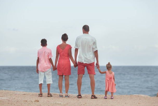 Velká šťastná rodina na procházce po pláži. Máma, táta a dvě děti. Modrá obloha, slunce, čerstvý mořský vítr. Potěšení z přírody a komunikace, venkovní - Fotografie, Obrázek