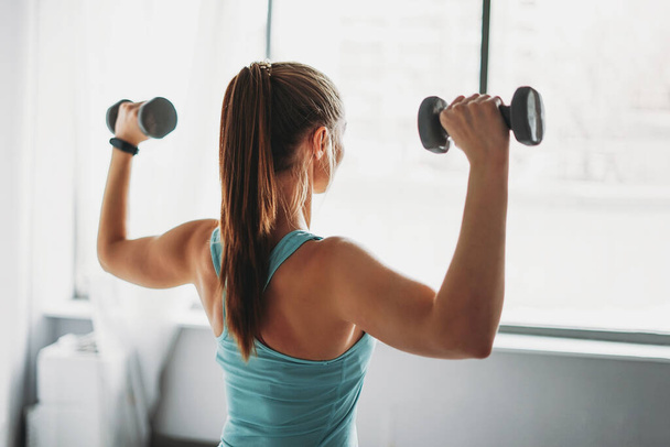 Attrayant ajustement jeune femme en tenue de sport modèle de fitness fille trains avec haltères à des cours d'entraînement en studio
 - Photo, image
