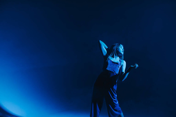 Νεαρό κομψό κορίτσι χορεύει στο στούντιο σε έγχρωμο φόντο νέον. Κλασικός χορευτής. - Φωτογραφία, εικόνα