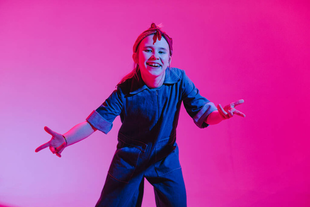 Молодая стильная девушка танцует в студии на цветном неоновом фоне. Дизайн музыкального плаката
. - Фото, изображение
