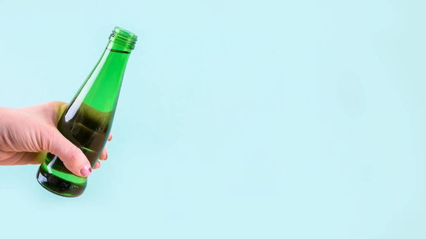 A glass water bottle is bright green on a light background. - Photo, image