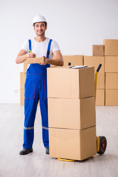 Jeune déménageur professionnel masculin faisant déménagement à la maison - Photo, image