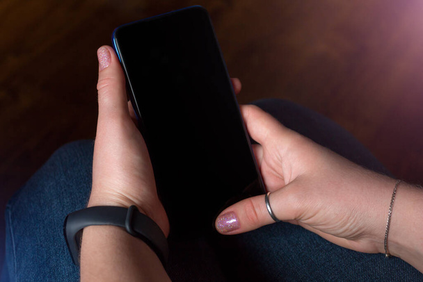 hands holding a mobile phone with a blank black screen mockup image - 写真・画像
