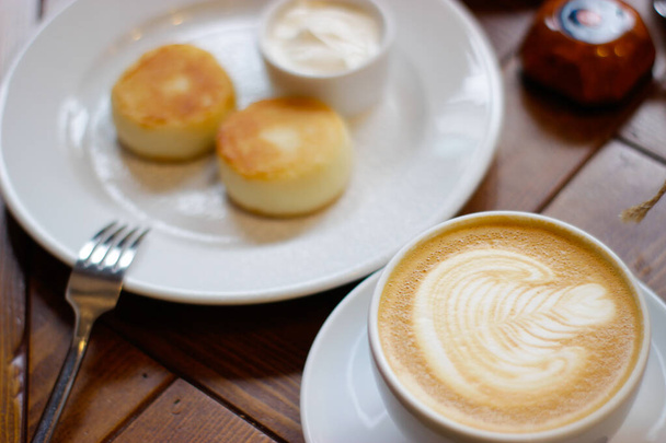 Cappuccino und Käsekuchen mit saurer Sahne auf einem Teller - Foto, Bild