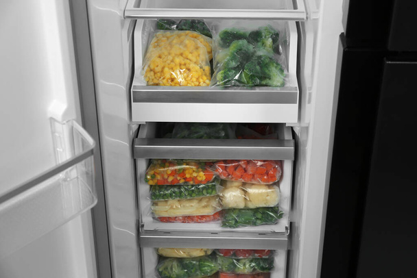 Buzdolabında farklı donmuş sebzeler olan plastik poşetler. - Fotoğraf, Görsel